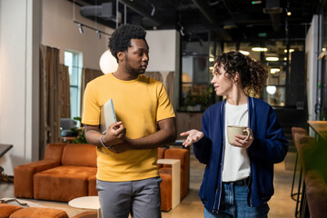 Fototapeta premium Woman holding coffee and man with notebook conversing