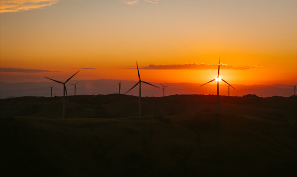 Wind Turbines On Hills During A Vibrant Orange Sunset