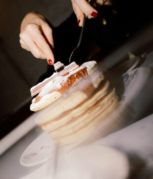 Woman using cutlery to eat a plate of pancakes with chocolate