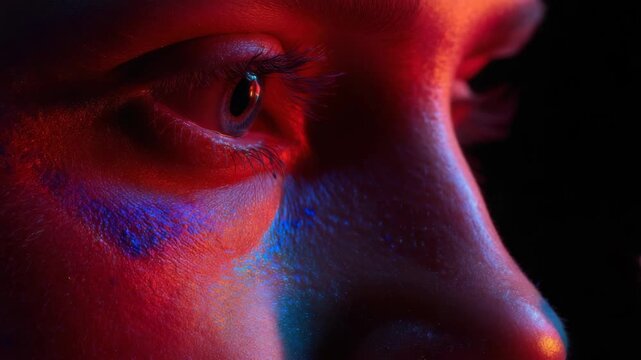 Close-up of a person's eye and cheek with colorful makeup being applied by a brush