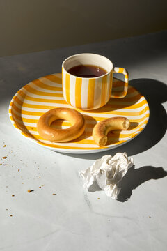 Leftovers from Breakast. Black Tea, Snacks and Crumbs on Striped Plate