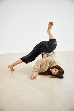 Woman performs yoga pose on light floor during indoor session