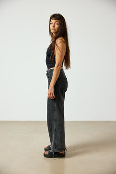 Woman poses in casual outfit against plain background in studio