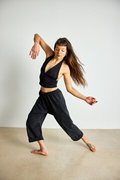 Dancer performing movement in studio space with plain background