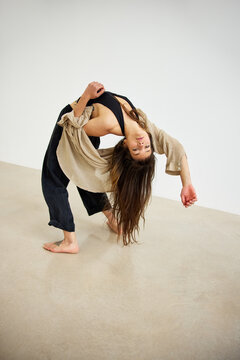 Woman performing a dance move in a studio during daylight hours