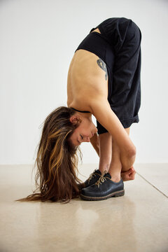 Woman stretches body while bending forward in a simple room