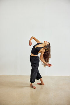 Dancer performs an expressive movement in a simple studio settin