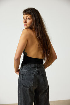Woman poses with back turned in casual setting with light backgr