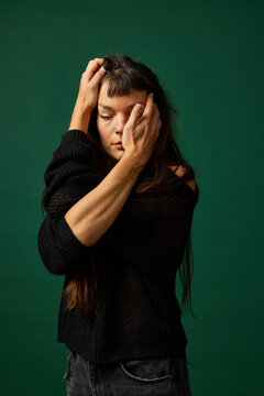 Woman poses emotionally against a green background for studio ph