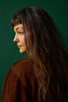 Model poses for a portrait in front of a green background