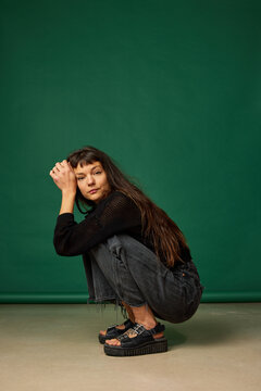 Woman crouching in front of green background during studio sessi