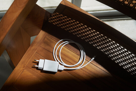 White charger and cable lying on wooden chair
