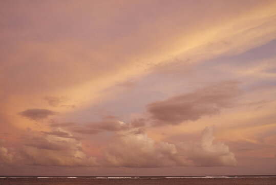 Sunset sky with clouds and soft colors over the calm ocean