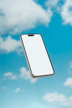 Smartphone floating against blue sky