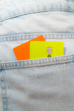 Green and orange cards in denim back pocket
