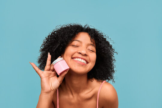 Smiling woman holding pink cosmetic jar