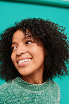 Woman with curly hair looking away while smiling