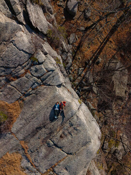 Two hikers lying on rocky cliff ledge