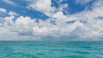 Obraz premium Turquoise ocean stretching under expansive cloudy sky at horizon.