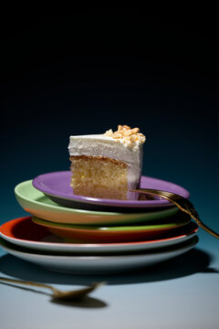 Slice of cake with frosting and nuts on colorful plates, studio shot