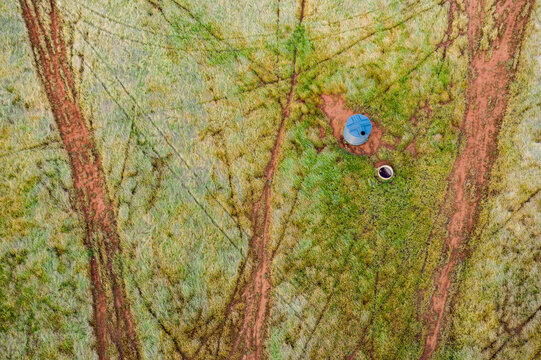 Animal tracks criss crossing a farm paddock around a water tank