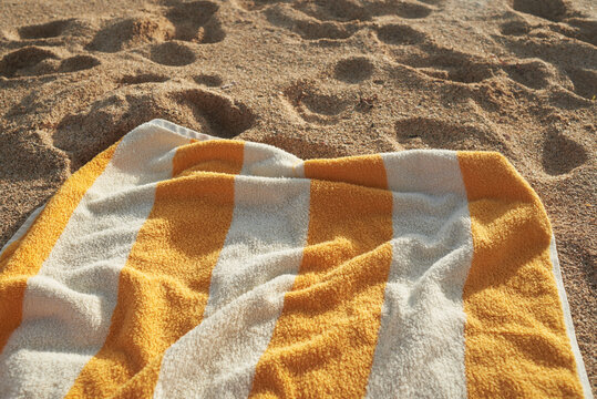 Striped yellow towel on sandy beach