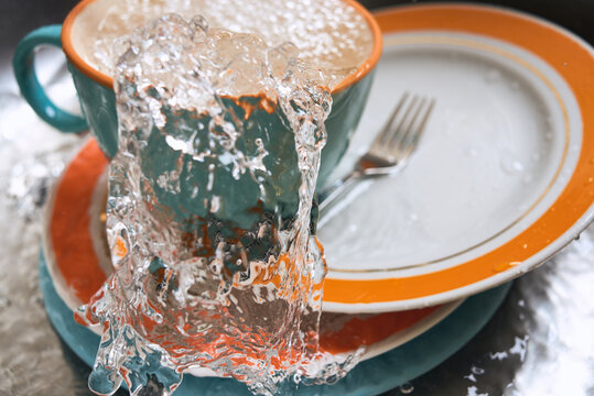 Cup spills water onto plates in a kitchen setting