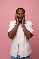 Obraz premium Surprised young african male in striped shirt against pink background