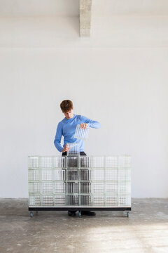 Man Stacking Glass Bricks On Cart In Studio