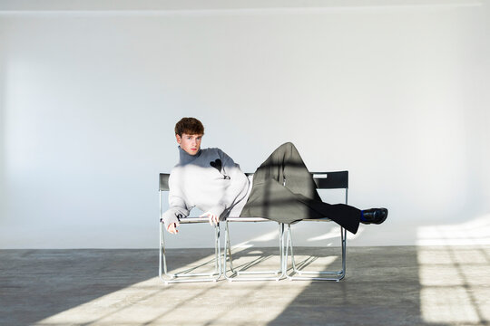 Relaxed Male Model Lying On Modern Studio Chairs
