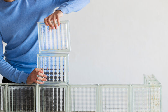 Person Stacks Glass Blocks Into Modern Wall Art
