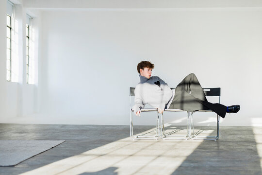 Relaxed Man Lounging on Modern Chairs in Studio