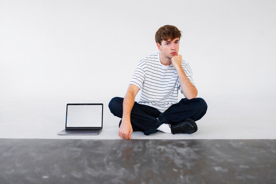 Thoughtful Young Man With Laptop In Studio