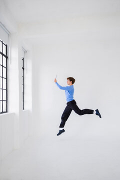 Man Jumping In White Studio With Tablet