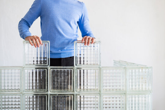 Man Building Glass Block Wall With Hands