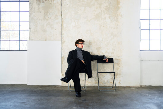 Man Seated on Folding Chair in Studio
