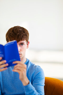 Young Man Reading Blue Book Indoors