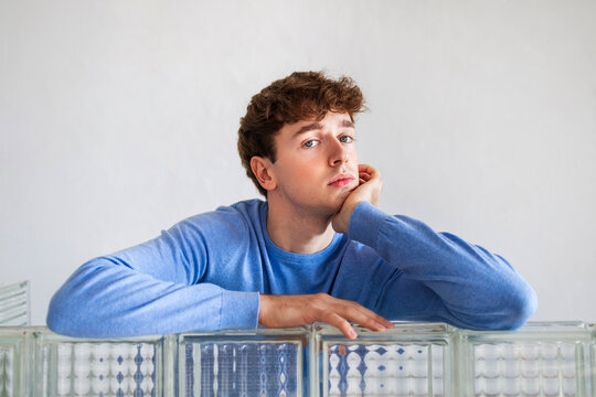 Thoughtful Young Man Resting Head on Hand in Blue Sweater