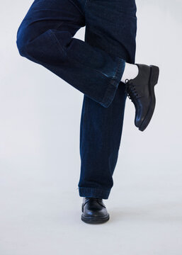 Lifted Leg In Dark Denim Jeans And Black Shoes