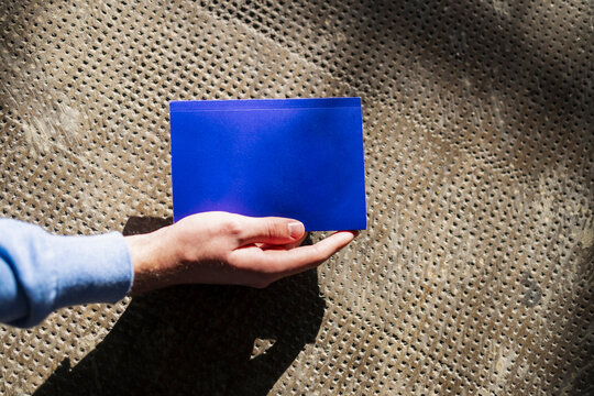 Blue Card Held by Hand on Textured Ground