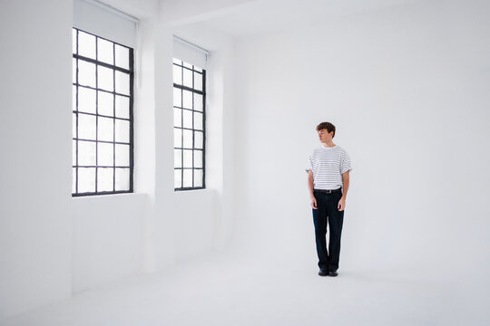 Man In Striped T-Shirt Stands In White Studio