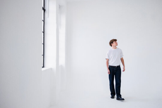 Man in Striped Shirt Standing in Bright Studio