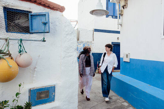 Women friends walking street in coastal fishing village Gran Canaria
