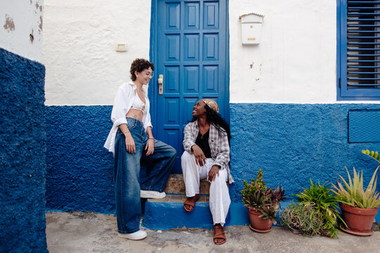 Diverse young women friendly talking outside blue building