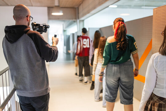 Teacher filming students dancing in school hallway