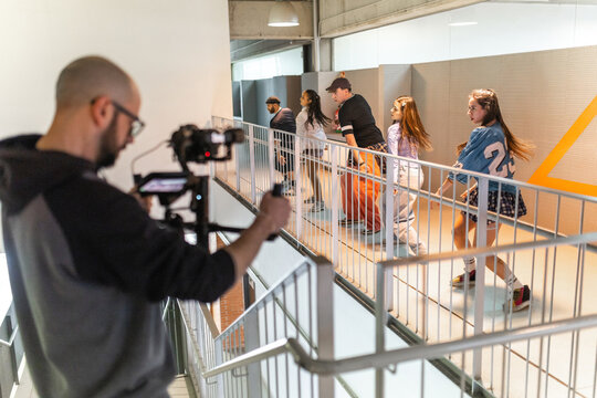 Teacher filming students dancing in school hallway