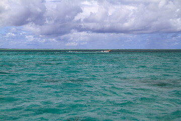 Motorboat anchored in the serene turquoise ocean beside a sandy beach