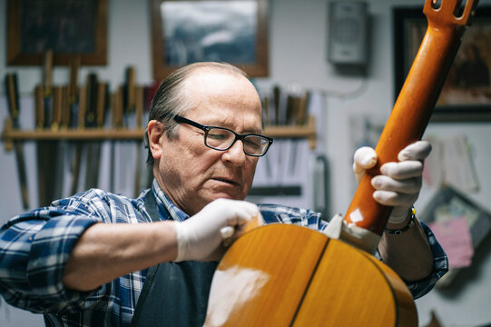 Luthier carefully restoring classical guitar in workshop