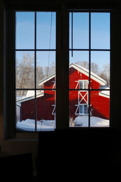 Window view of a red barn in winter
