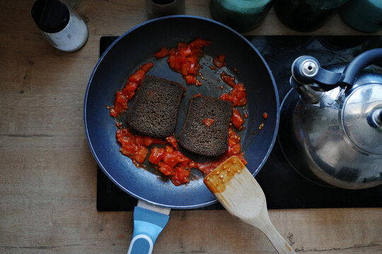 Cooking rye bread and diced tomatoes in a frying pan